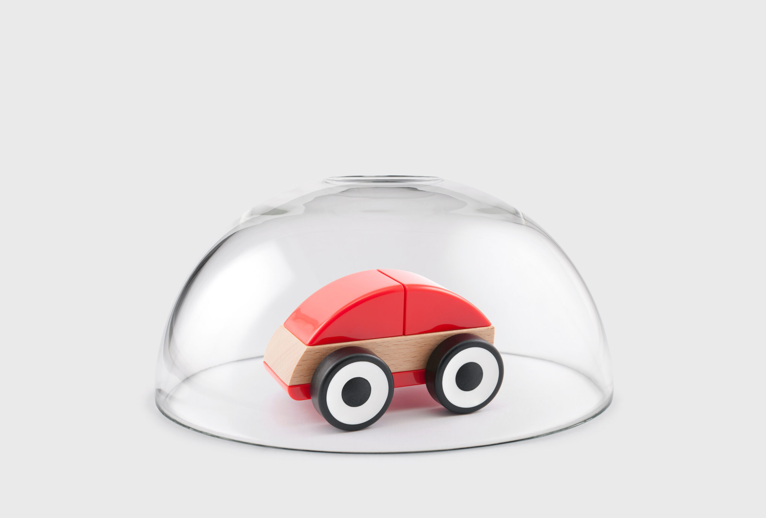 Red toy car protected under a glass dome